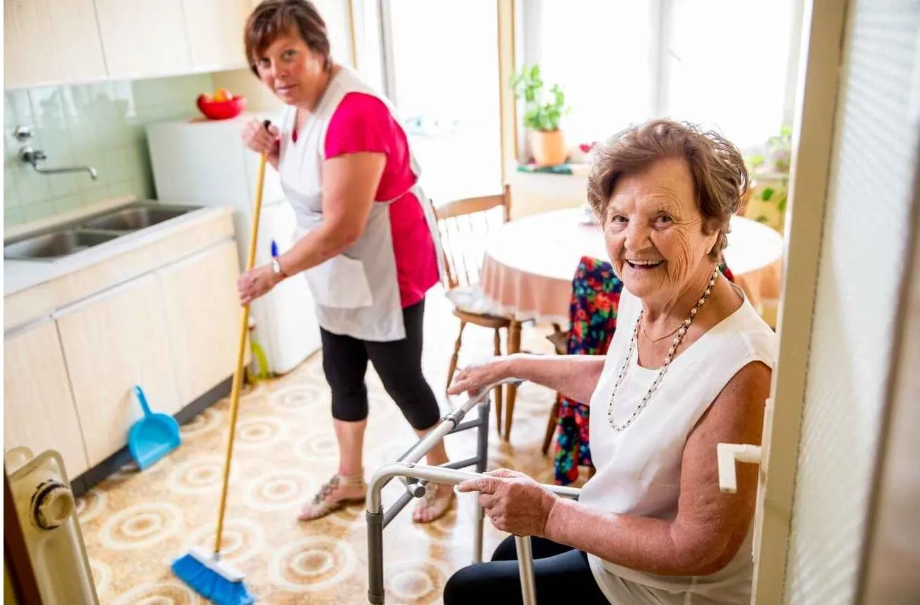 Who Needs A Caregiver: Inability To Take Care Of Home - caregiver helping elderly woman sweep the floor