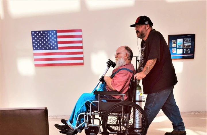 Man being wheeled in a wheelchair by another man 
