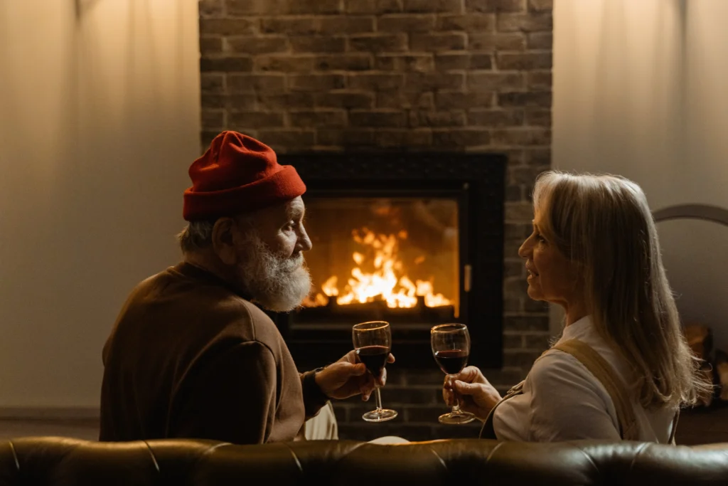 Elderly couple sitting in front of fireplace in house