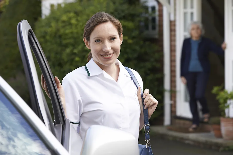 Reliable In-Home Care: Female caregiver stepping out of car to visit an elderly woman at her home