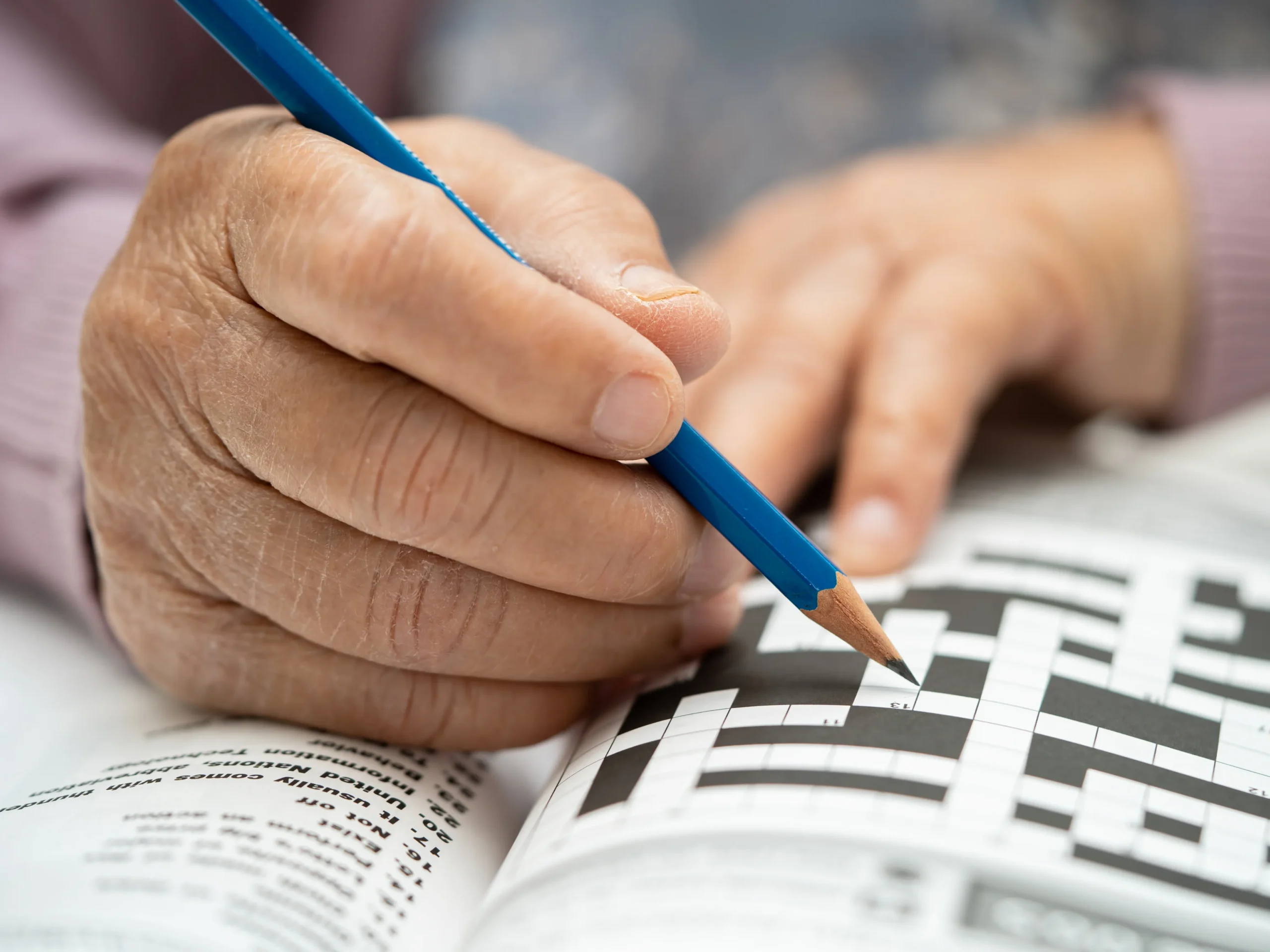 elderly hands doing a crossword - one of the memory games for seniors